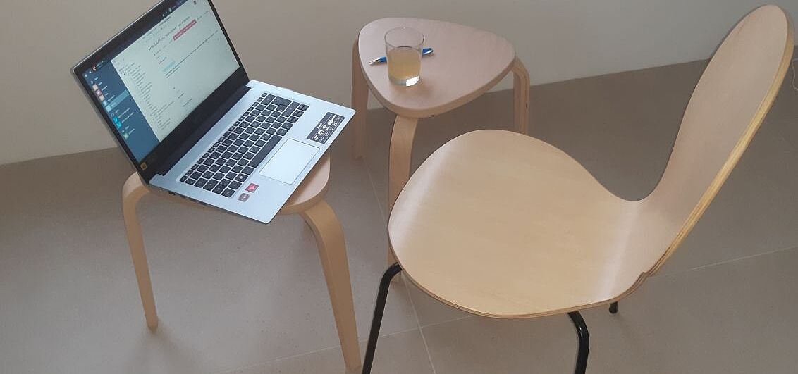 Laptop, Getränk und Stift vor einem Stuhl